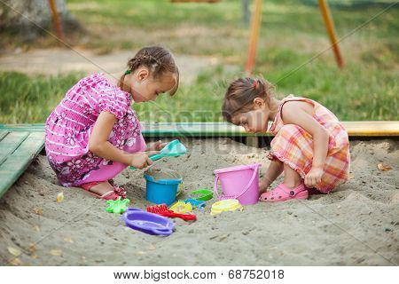 Two girls play in the sandbox