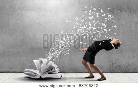 Young woman benting to evade characters flying from book