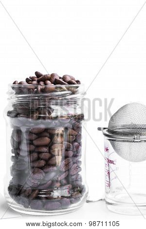 roasted coffee beans in retro glass jar with coffee shot glass and strainer