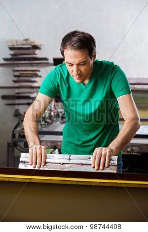 Mid adult man using squeegee in paper factory
