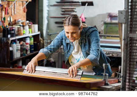 Smiling mid adult female worker using squeegee in factory