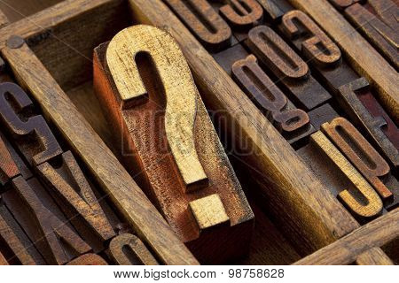 question mark - vintage wooden letterpress type block in old typesetter drawer among other letters stained by color inks