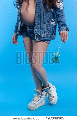 Lollipop in hand of pregnant woman. Food whims of mother-to-be and unhealthy diet