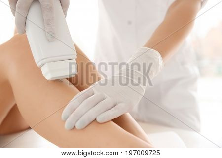 Woman having hair removal procedure on leg with wax depilatory in salon. Depilation concept