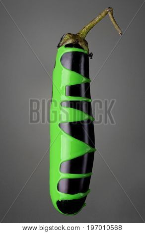 Eggplant With Pouring Toxic Green Paint On Gray Background. Fashion Food Concept.creative.