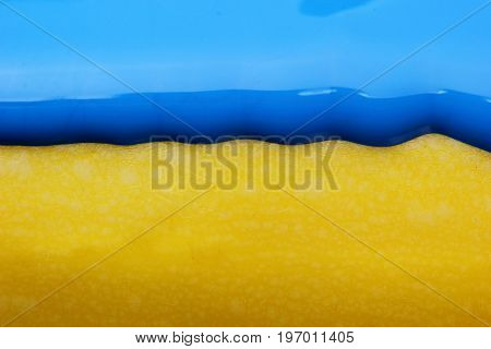 Pouring blue paint over yellow background, macro closeup.Texture.Abstract