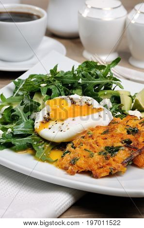 Brunch Idea. Egg poached with pumpkin spinach pancakes and garnish from arugula avocado mint leaves and ricotta