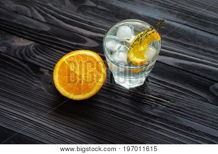 Cut orange near the alcoholic cocktail on dark wood table top view. Blank space for text placement