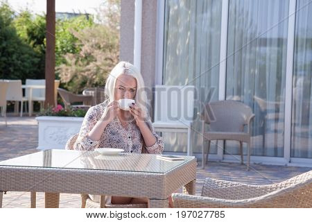 blonde girl sitting at the beach restaurant coffee drinkers