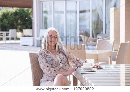 blonde girl sitting at the beach restaurant coffee drinkers