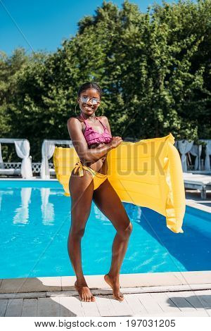 Young Beautiful Black Woman Posing With Inflatable Mattress At Poolside At Resort