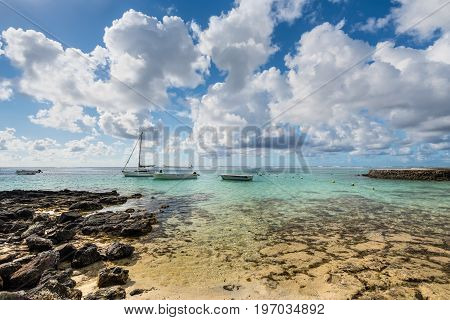 Blue Bay Mauritius - December 28 2015: Boats moored at the Blue Bay Marine Park Mauritius Mahebourg Indian Ocean. Stones in the foreground. Polarizer filter used.