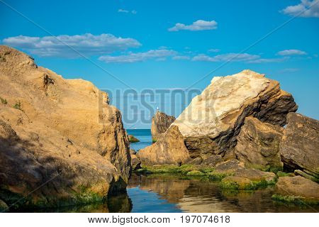 Seascape of calm blue ocean and rocky shore in the foreground