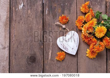 Fresh orange autumnal flowers chrisanthemum and heart on vintage wooden background. Selective focus. Place for text.