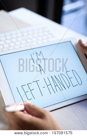 closeup of a young left-handed man handwriting the text I am a left-handed in digital tablet with an active pen