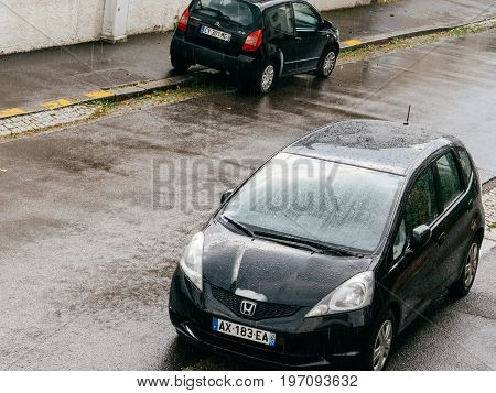 STRASBOURG FRANCE - MAY 30 2016: Rain drops falling over aerial view of a Honda Fit and Citroen C2 parked on French street