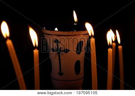 Lampade surrounded by burning candles on a black background