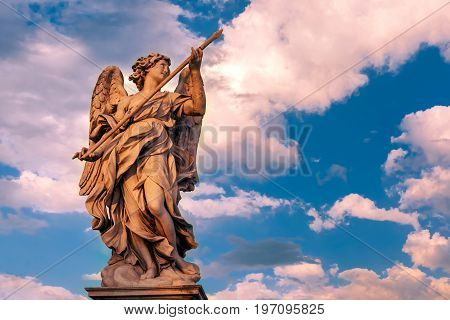 Marble statue of Angel with the Lance at sunset, one of the ten angels on Saint Angel Bridge, symbols of Christ's Passion, Rome, Italy