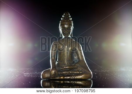 Traditional buddha figurine in meditation pose. Bronze buddhist statue backlit to show spiritual enlightenment.