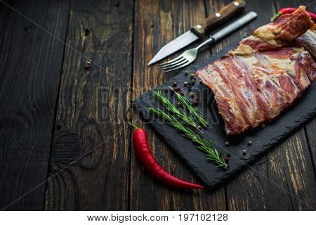 Cooked ribs with meat and a fork with a knife next to a shallow depth of field