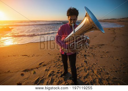 Musician instrumentalist playing the Tuba on the sea coast. 