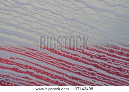 Soap foam pattern and bubbles on glass with red and white backgraund. Detailed  texture.