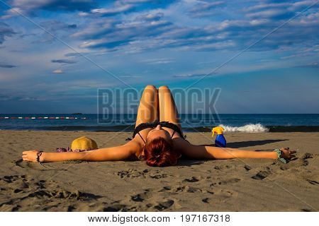 Young Good Looking Tanned Redhead Laying On A Sandy Beach With Arms Resting And Leg Resting And Happ