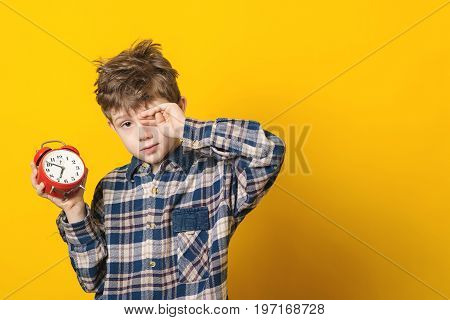 Little Boy Waking Up With Alarm Clock, Isolated On Yellow Background.