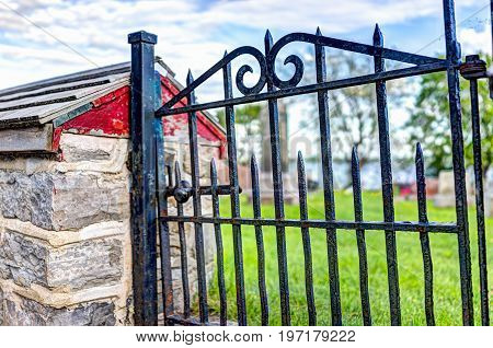 Closeup of small red metal gate to cemetary by church in summer in Europe