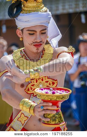 CHIANGMAI THAILAND - JANUARY 25 2015: Indigenous dancer man with traditional costume holding tray with pedestal of flower dancing in parade of 22nd Traditional Skirt Fabric and The Indigenous Product and Culture Festival in Mae Chaem Chiangmai Thailand