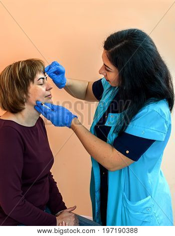 Eyebrow correction. Correcting the form. Drawing of a line of eyebrows in a beauty salon.