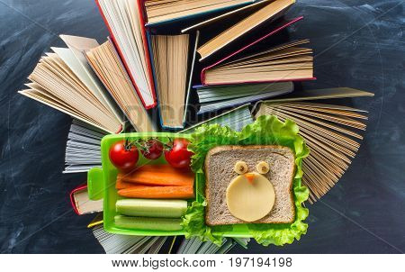Some books with lunche box on the desk over the blackboard