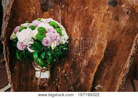 Rustic wedding bouquet with different flowers and greens on wooden background. Top view.