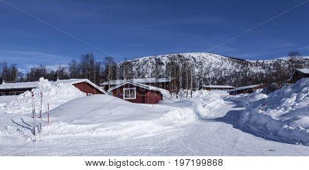 KLIPPEN, SWEDEN ON MARCH 19. View of some red lodges, cabins in winter snow on March 19, 2017 in Klippen, Sweden. Sunshine, roads and mountains. Editorial use.