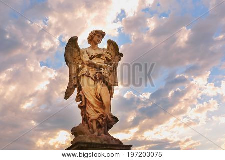 Marble statue of Angel with the Whips at sunset, one of the ten angels on Saint Angel Bridge, symbols of Christ's Passion, Rome, Italy