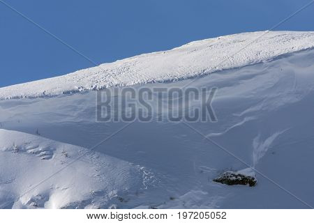 Rocks, cliffs on a mountain slope. Winter, snow and snow-pack.
