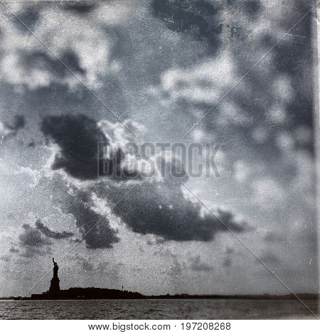 Vintage filter effect of the Statue of Liberty and clouds in New York Harbor on the East River. TinType / Wet plate effect. Black and White. 