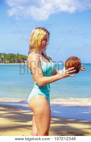 Young girl holding coconut on the beach