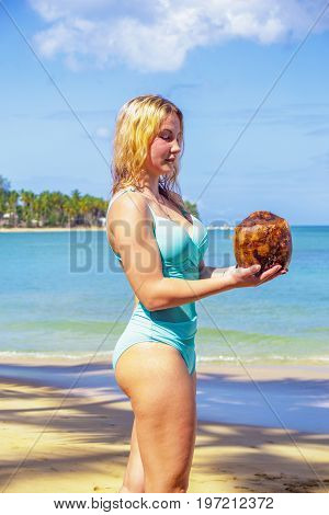 Young girl holding coconut on the beach