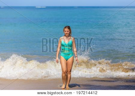 the girl in blue comes from the sea to the sandy beach