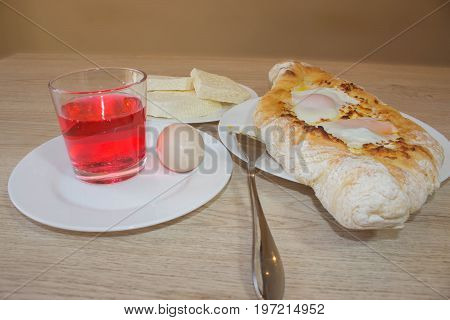 Adjarian Khachapuri - georgian cheese pie with egg. Adjarian khachapuri on a on a plate. Open pie with cheese in the shape of the boat