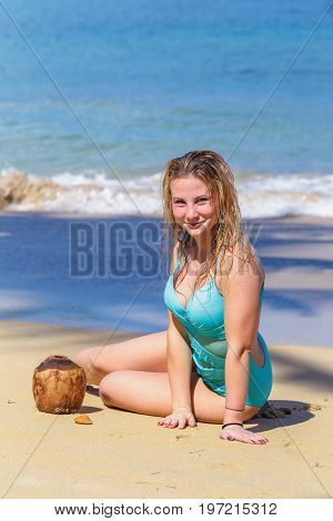 young pretty girl sitting on the beach with coconut