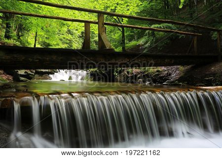 bridge over small watrfall on mountain river