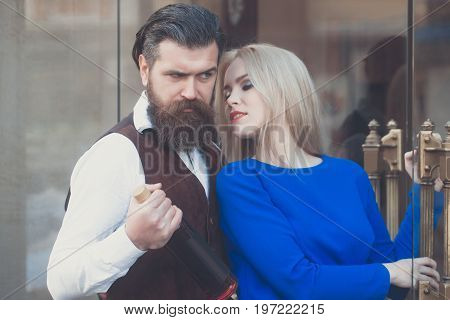 Woman And Man Standing At Glass Door With Bottle