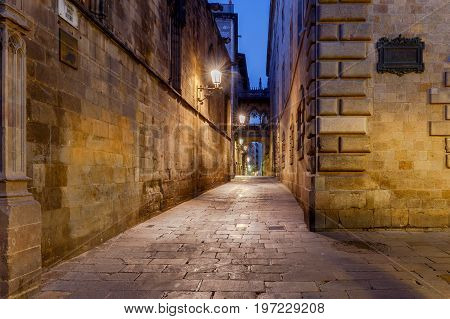 Narrow medieval street Carrer del Bisbe and bridge of sighs in the Gothic quarter of Barrie at dawn. Barcelona. Spain.
