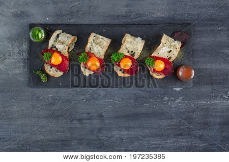 Four tiny appetizers with cured met, yolk and parmegano cheese on stone board with copyspace. Top view.