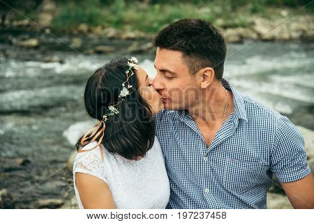couple standing and hugging near mountain river with mountains on background
