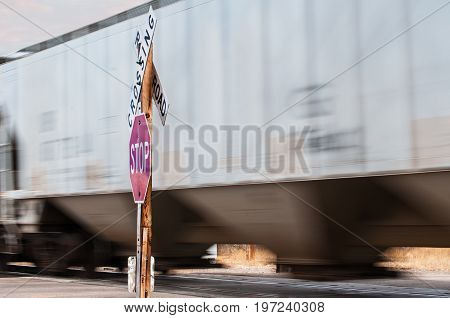 Railcars carrying bulk freight at a railroad crossing marked by a stopsign and RR warning sign.