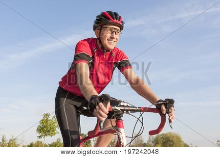 Cycling Concepts. Smiling Professional Road Cyclist During Ride on Bike Outdoors. Completely Equipped in Professional Outfit.Horizontal Image