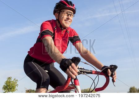 Cycling Concepts. Smiling Professional Road Cyclist During Ride on Bike Outdoors. Completely Equipped in Professional Outfit.Horizontal Shot
